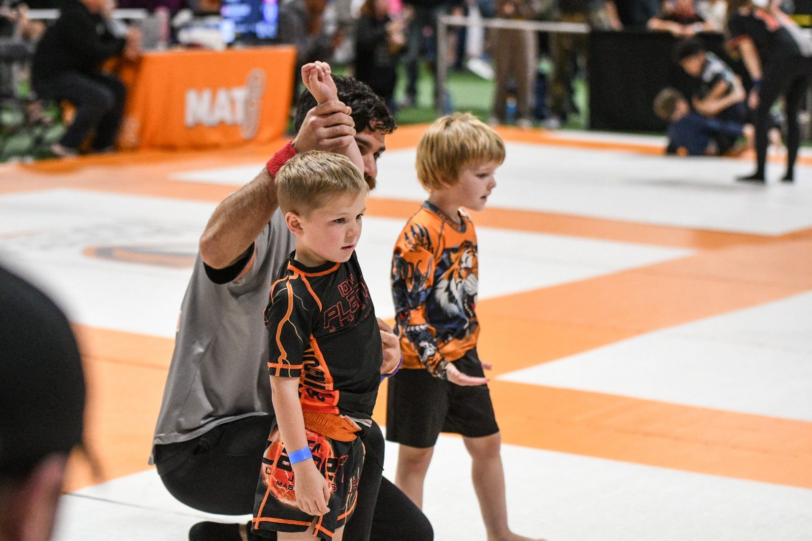 A 10th Planet Masury coach raising a young student’s hand after a match