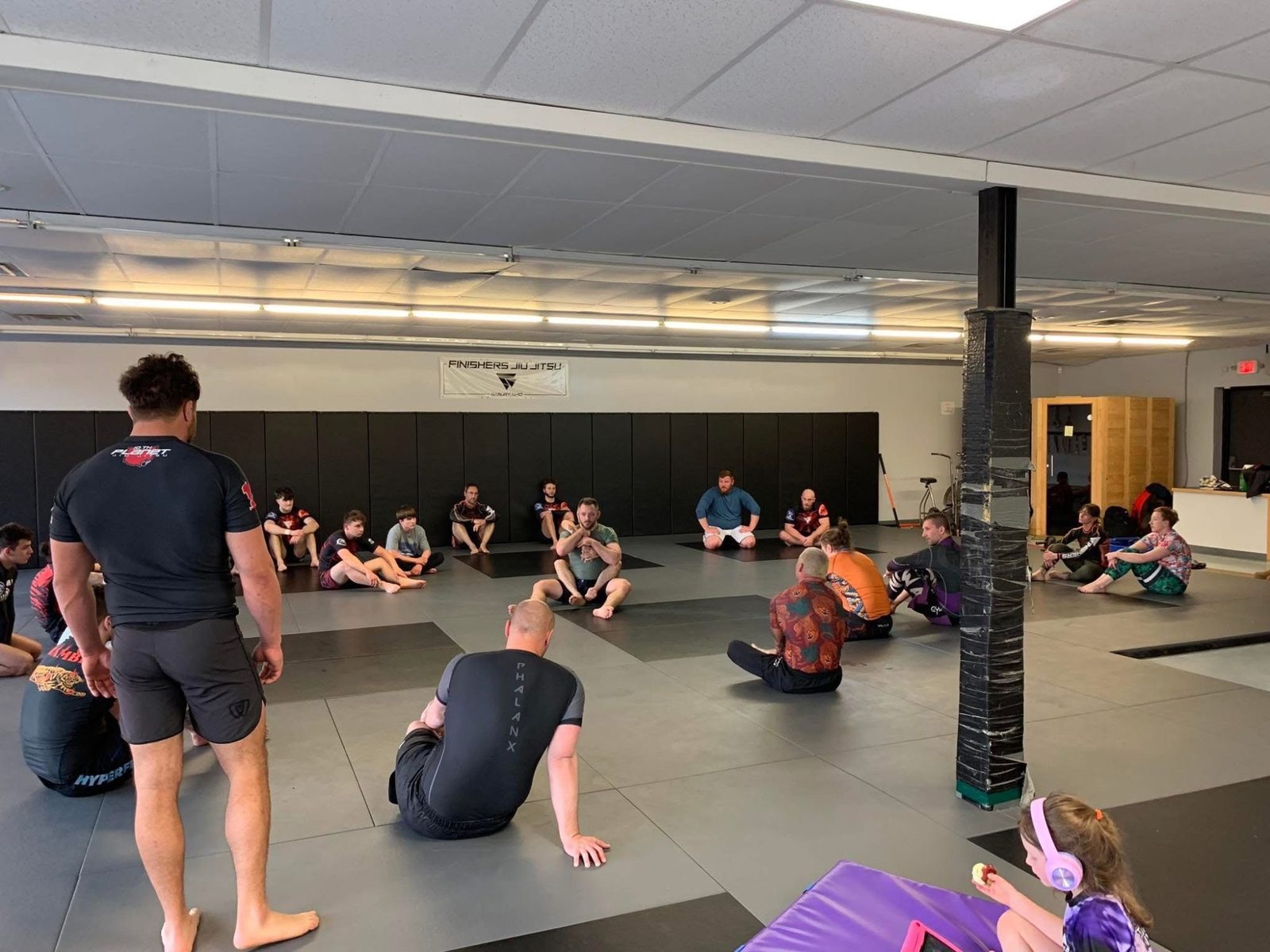 A coach addressing the adults class from the mat
